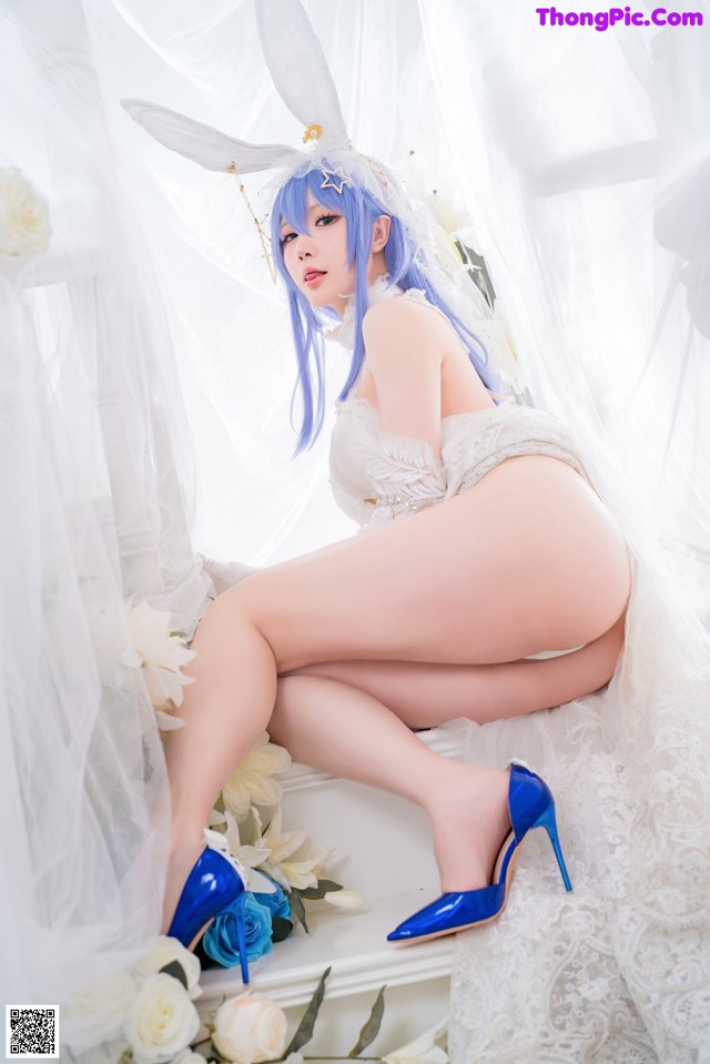 A woman in a bunny costume sitting on a bed of flowers.