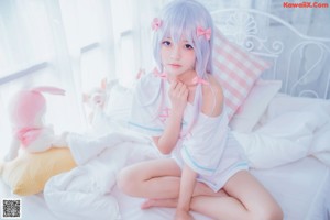 A woman in a pink dress sitting on a bed with a stuffed animal.