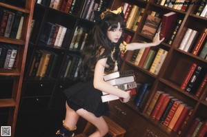 A woman sitting on top of a table next to a book shelf.