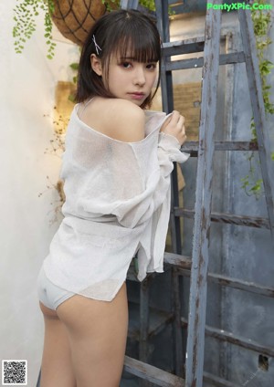 A woman in a gray bodysuit leaning against a ladder.