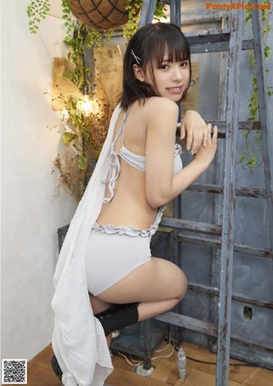 A woman sitting on top of a ladder next to a wall.