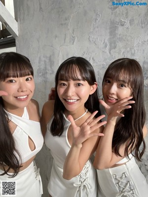 A group of three women sitting on top of a white couch.