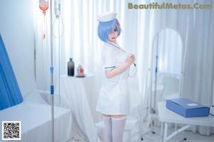 A woman dressed as a nurse standing in a hospital room.