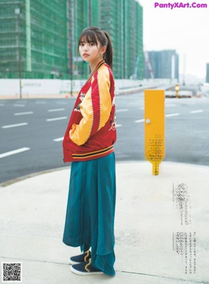 A woman in a yellow jacket and green dress posing for a magazine.