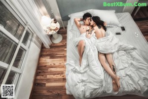 A man and a woman sitting on a bed together.