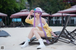 A woman with long purple hair sitting on a chair.