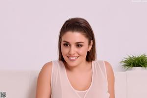 A woman in a white top and floral shorts posing for the camera.