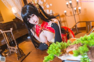 A woman in a red and black outfit sitting on a wooden bench.