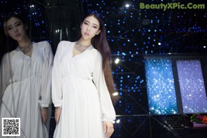 A woman in a white robe standing in a shower.