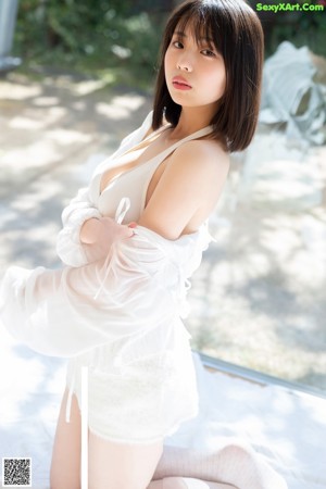 A woman in a white lingerie sitting on a bed.