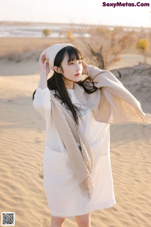 A woman standing in the middle of a desert.
