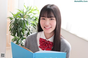 A young woman in a school uniform sitting on a chair.