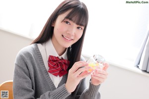 A young woman in a school uniform sitting on a window sill.