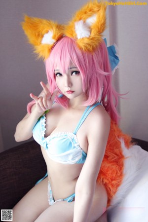 A woman in a blue bikini with pink hair and fox ears.