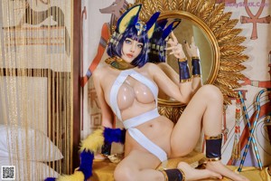 A woman in a blue and yellow costume is posing on a bed.