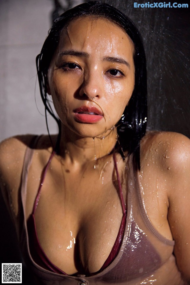 A woman in a shower with water droplets on her face.