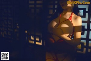 A woman in a red lingerie standing in front of a mirror.