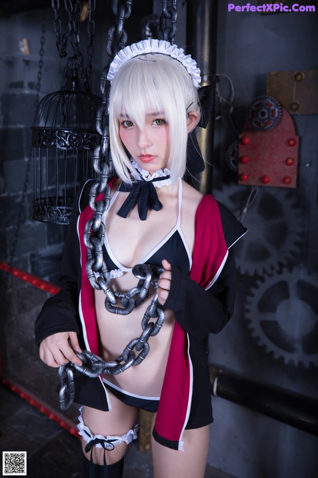 A woman in a maid outfit holding a chain.