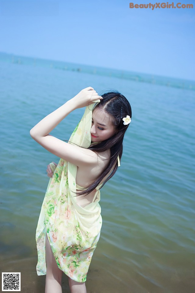 A woman in a yellow dress standing in the water.