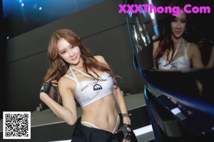 A woman in a white top and black pants posing for a picture.