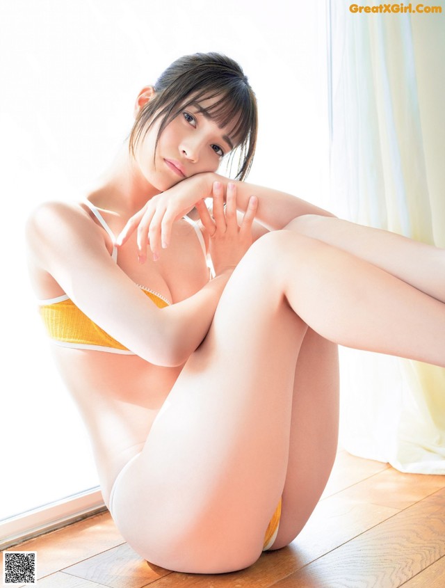 A woman in a yellow bikini sitting on the floor.