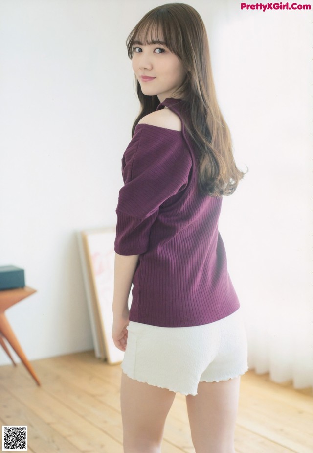 a woman wearing a purple sweater and white shorts