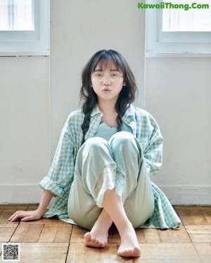 A woman sitting in a chair in front of a window.