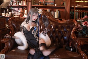 A woman sitting on a chair holding a fan in her hand.