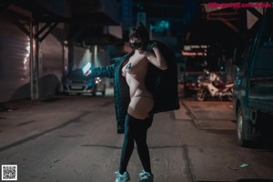 A woman in a black jacket and blue shoes posing for a picture.