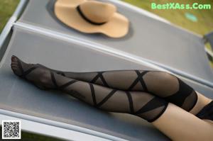 A woman in a black bodysuit sitting on the edge of a pool.