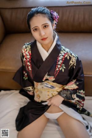 A woman in a kimono sitting on a couch.