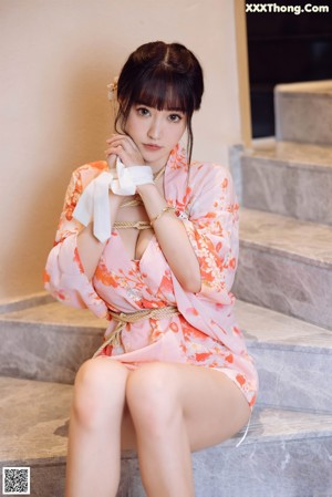 A woman in a pink kimono sitting on some steps.