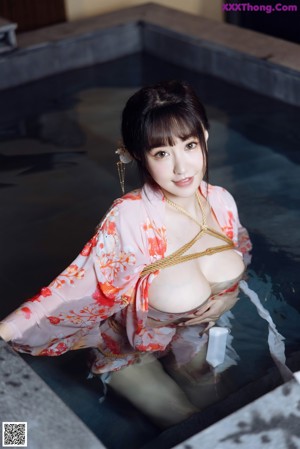 A woman in a pink kimono is tied up in a bathtub.