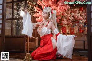 A woman in a white and red outfit sitting on a wooden floor.