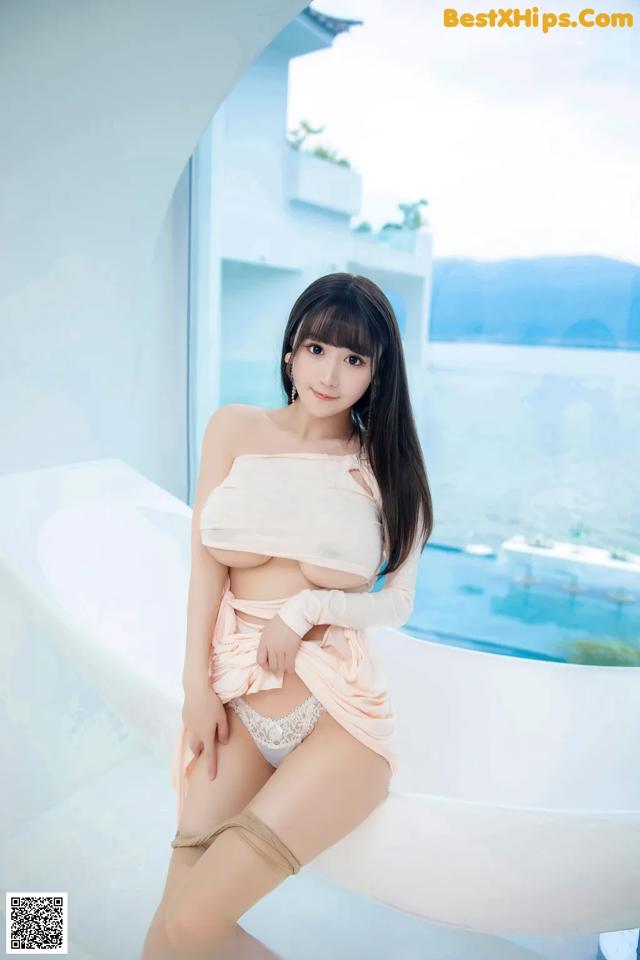 A woman sitting on top of a bathtub next to a pool.