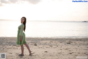 A woman in a green bra and black panties on the beach.