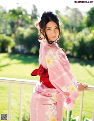 A woman in a pink kimono with a red flower in her hair.