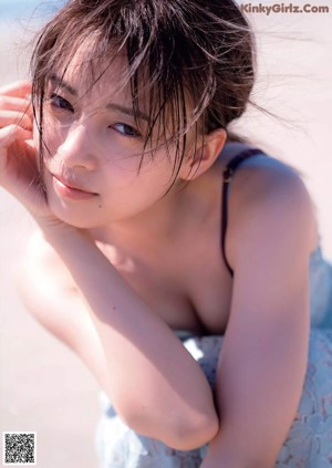 A woman in a green bikini leaning against a wall.