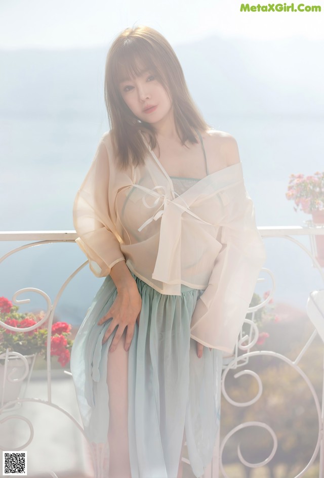 A woman standing on a balcony next to the ocean.