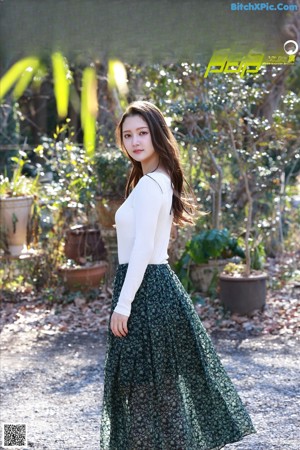 A woman standing in the middle of a road with trees in the background.