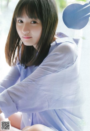 A young woman in a school uniform with a towel over her head.