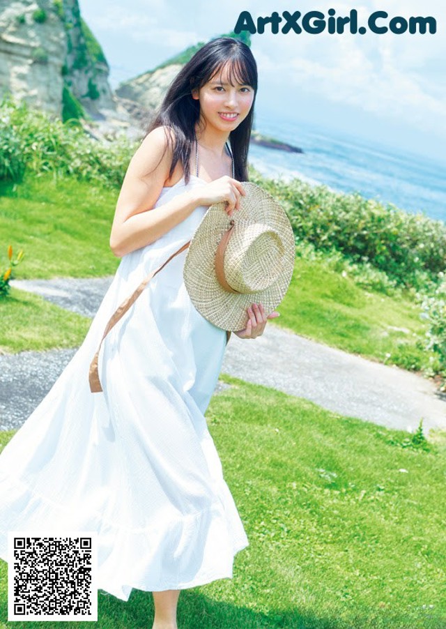 A woman in a white dress holding a straw hat.