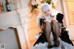 A woman in a black and white dress sitting on a white chair.