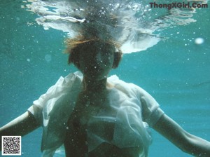 A woman in a white dress floating in the water.